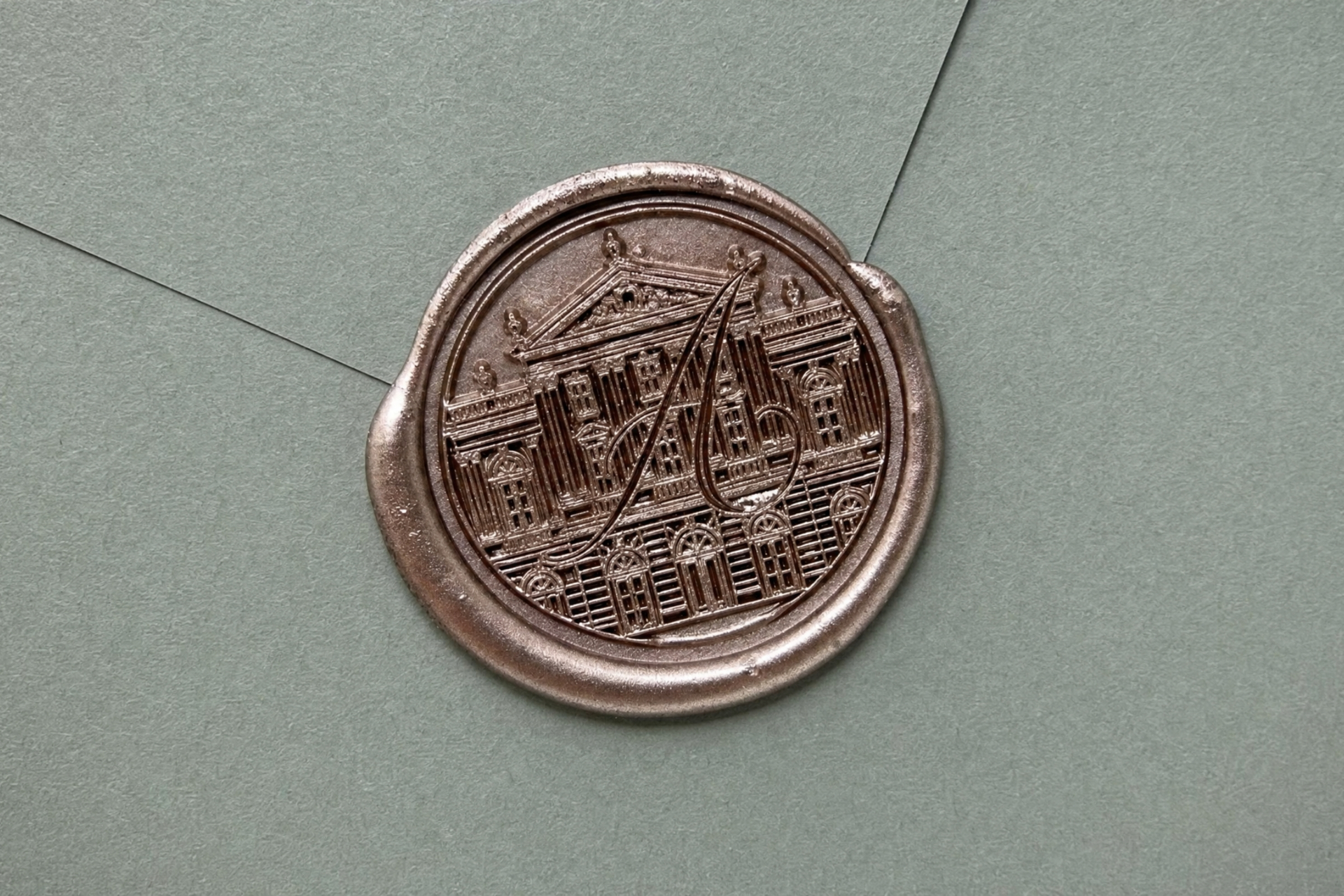 Sceau de cire cuivrée pressé sur une enveloppe verte : détail macro du blason « A ».